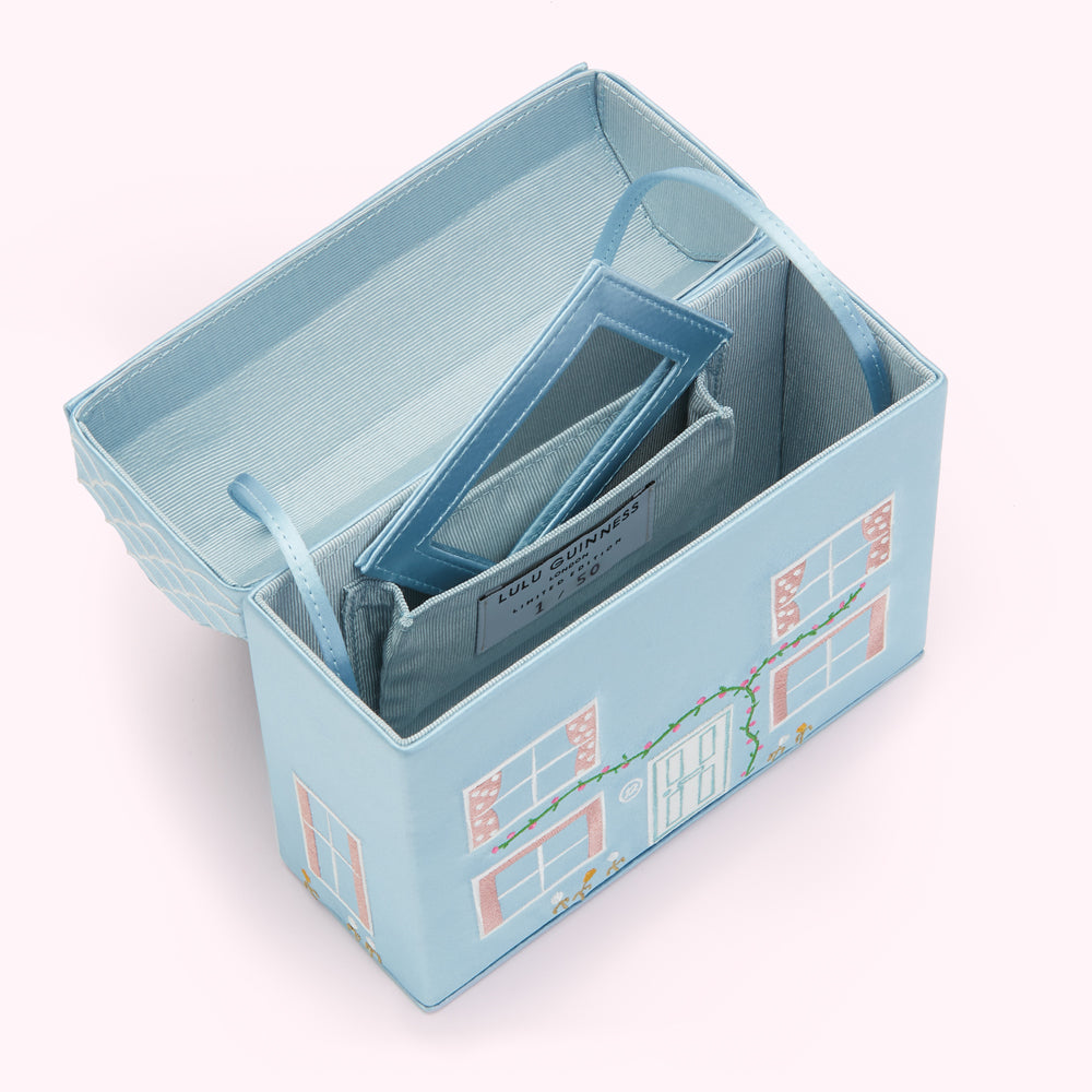 Open light blue Lulu Guinness house-shaped clutch with a mirror and label visible inside.