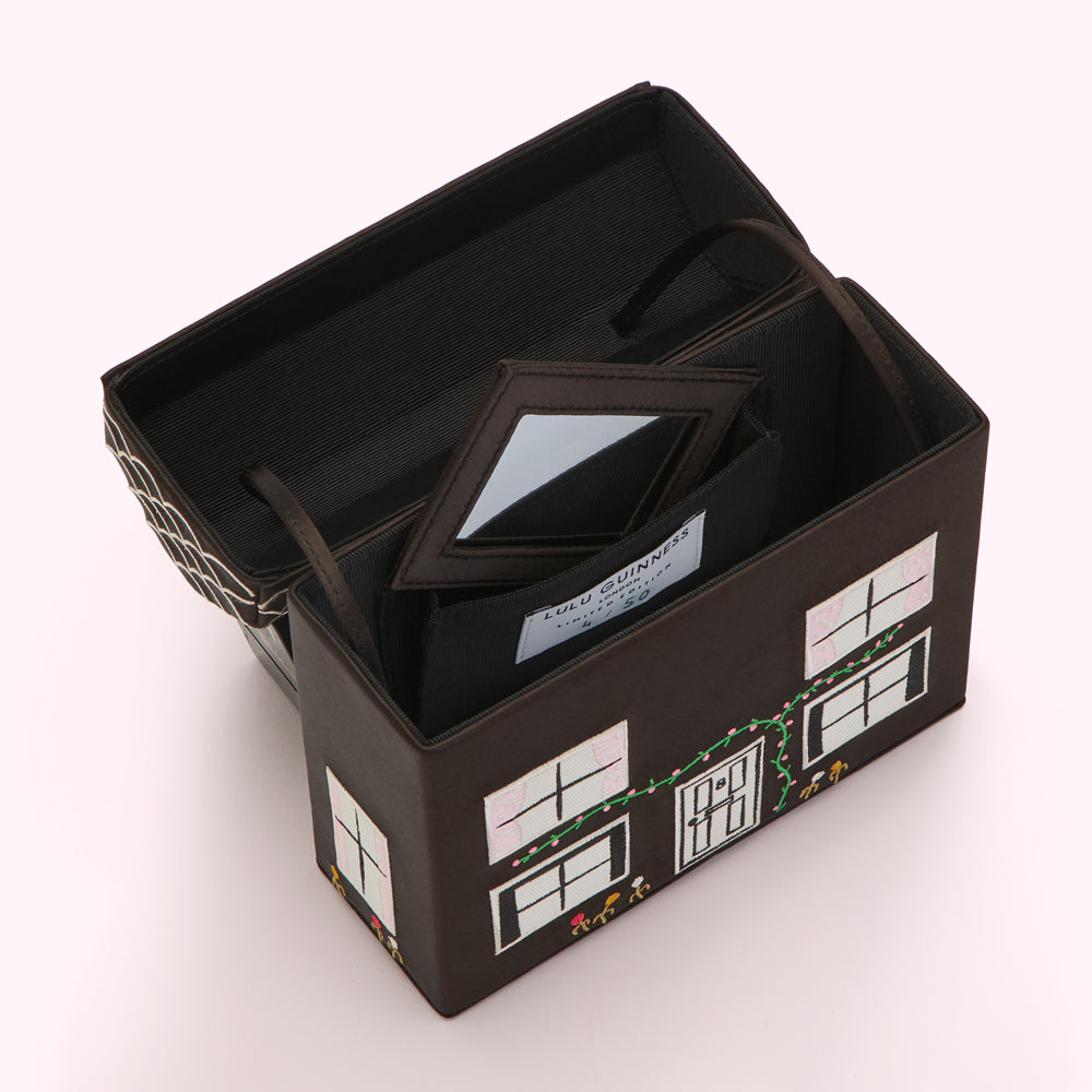 Open dark brown Lulu Guinness house-shaped cosmetic case with interior mirror and compartments.
