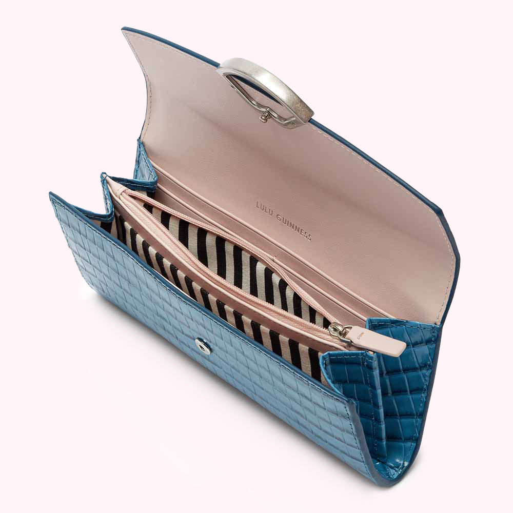 Open blue crocodile-embossed Lulu Guinness wallet with pink interior and silver ring detail.
