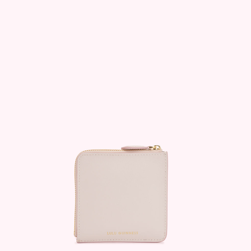 A pale pink zip-around purse by Lulu Guinness, against a white background.
