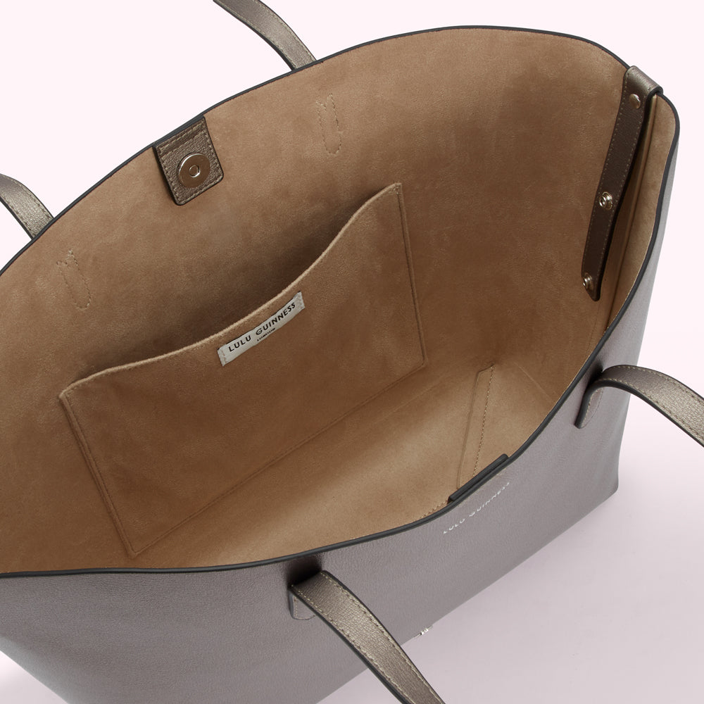 Inside of a grey Lulu Guinness tote bag showing beige lining and interior pocket.