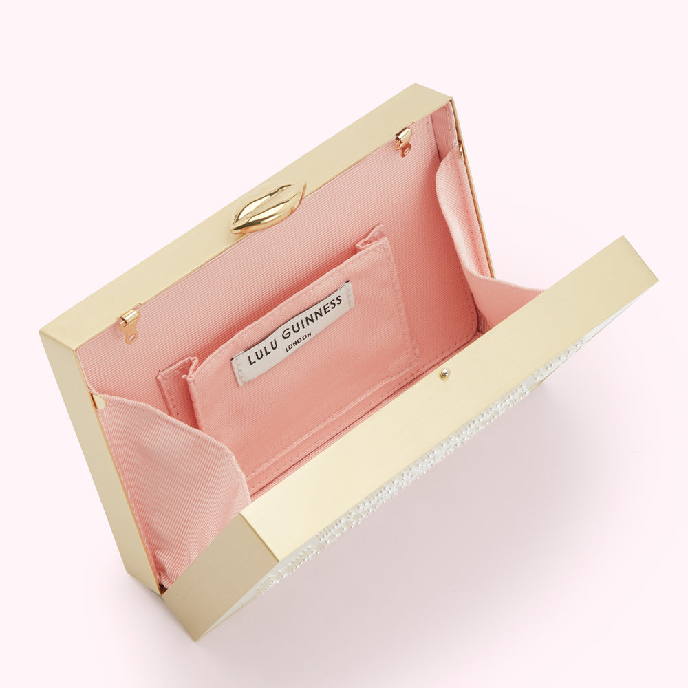 Open gold Lulu Guinness box clutch with pink lining and pearl embellishments.
