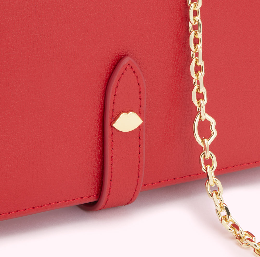 Close-up of a red leather wallet with a gold chain and lip-shaped detail.