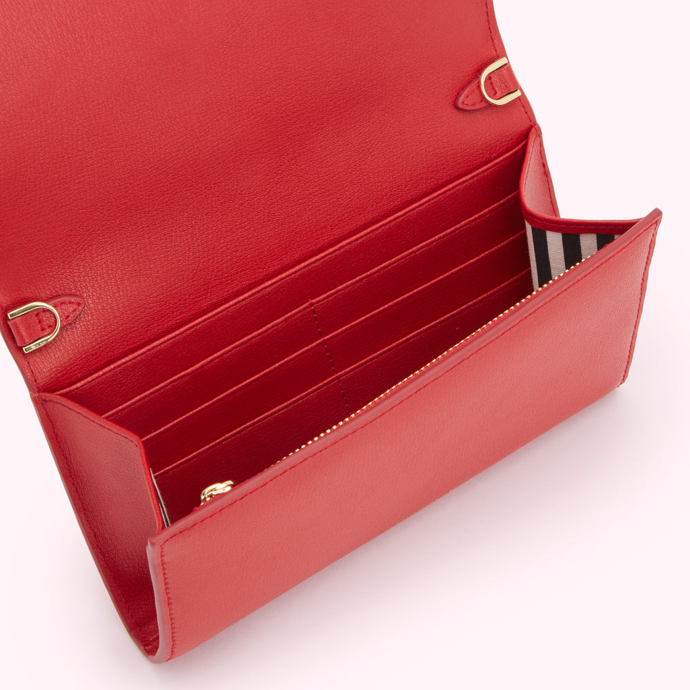 Open red leather wallet with gold hardware and black and white striped interior.
