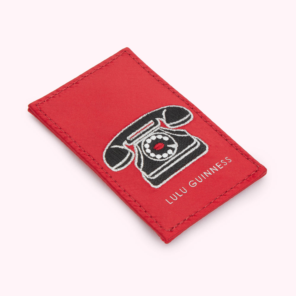 Red satin Lulu Guinness mirror with an embroidered black rotary telephone.
