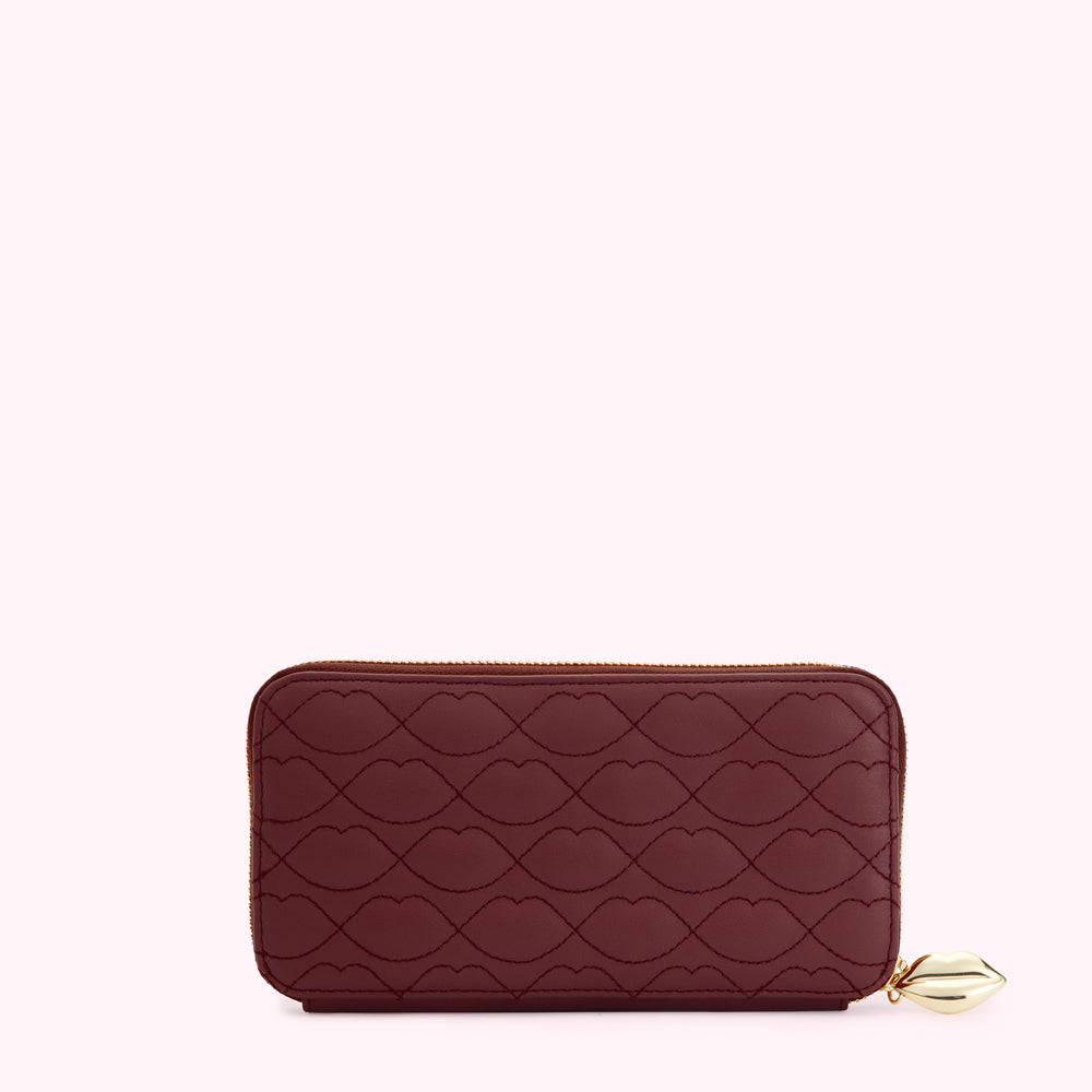 Burgundy zip-around wallet with embossed lip pattern and gold lip charm.
