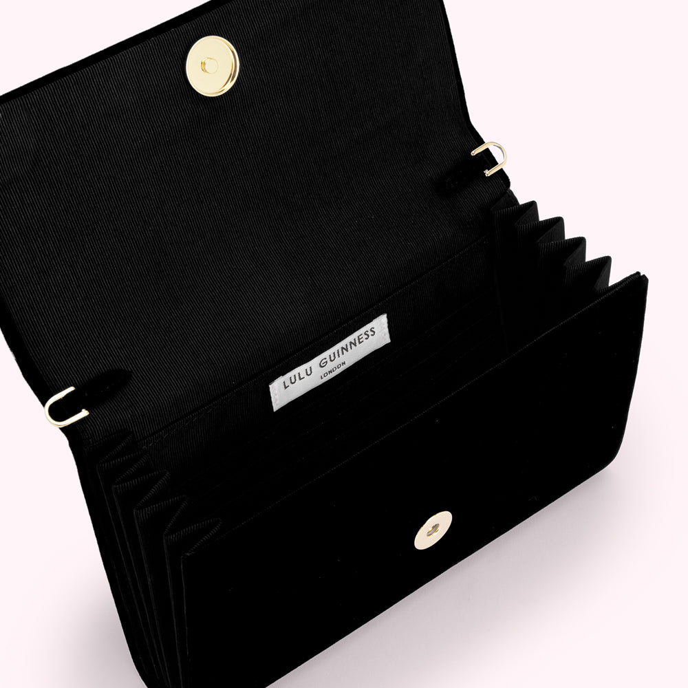 Open black velvet Lulu Guinness London clutch purse with gold clasp and interior label.
