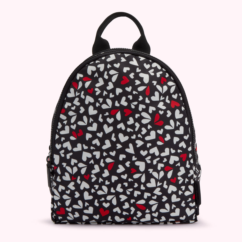 Black backpack with a pattern of white and red hearts.