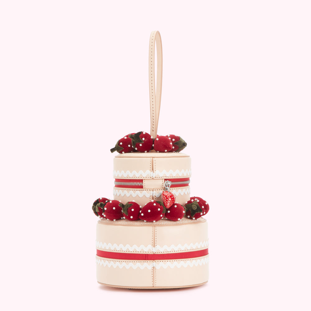 Two-tiered strawberry cake-shaped handbag with a beige background.