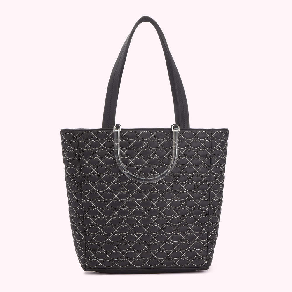 Black quilted tote bag with lip-shaped pattern and clear handles.
