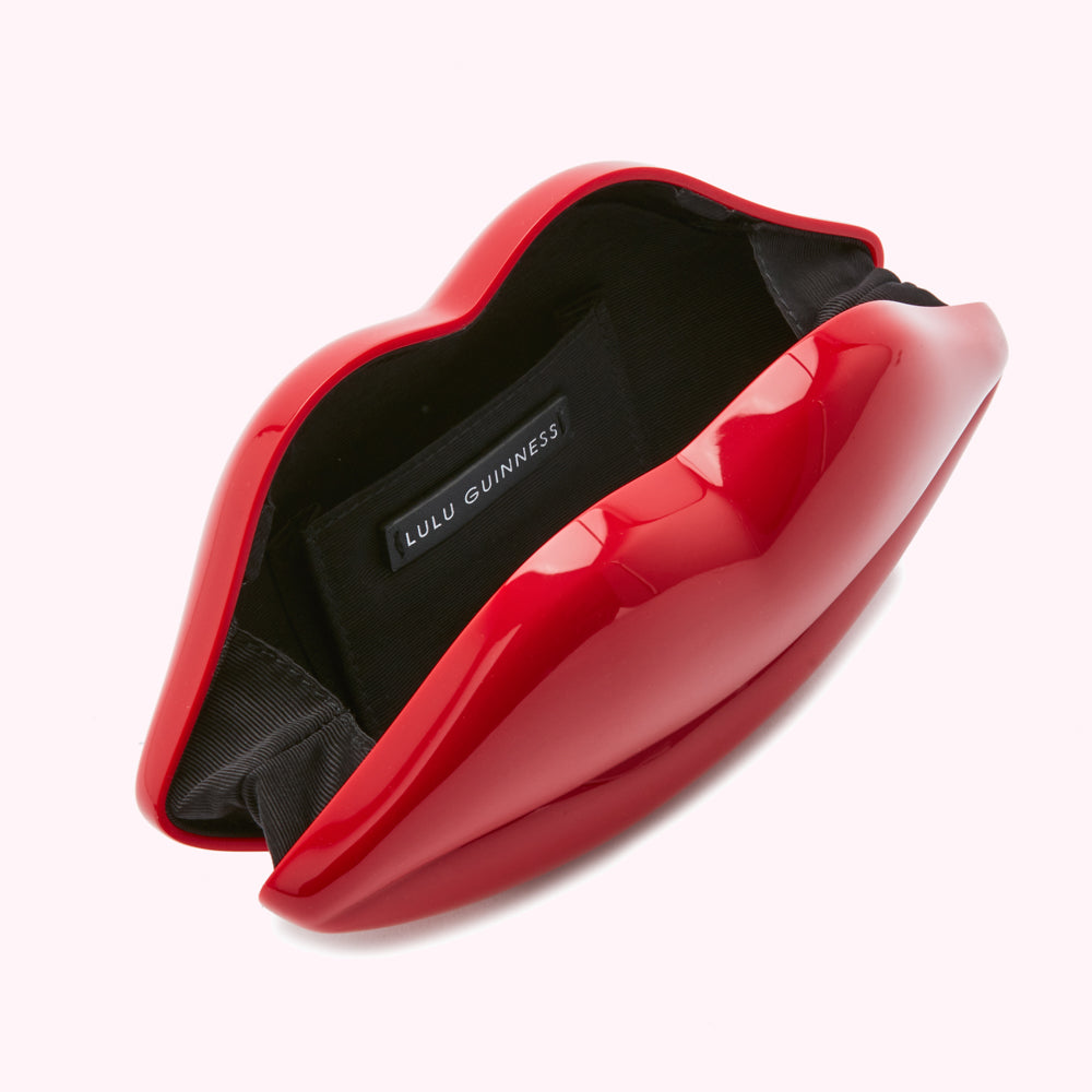 Red Lulu Guinness lip-shaped clutch open to reveal black interior and brand label.

