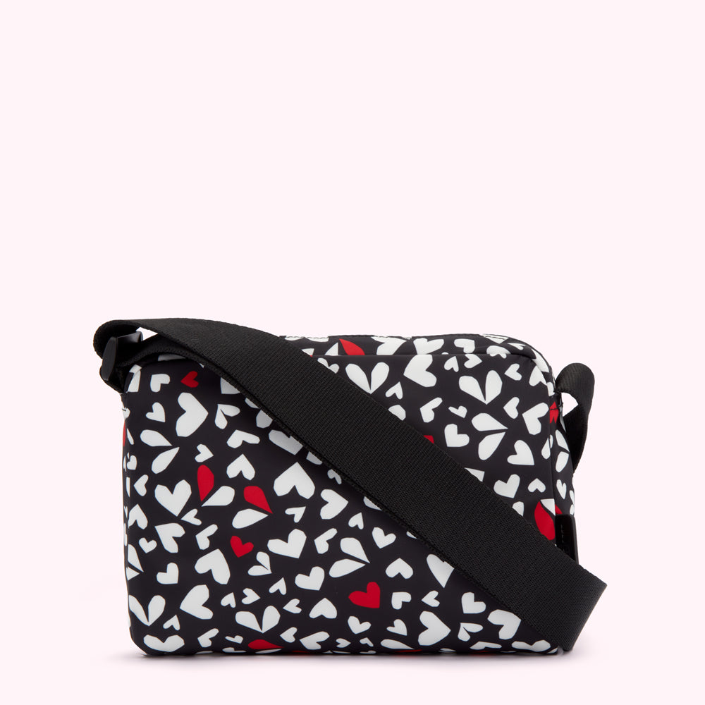 Black crossbody bag with a white and red heart pattern.
