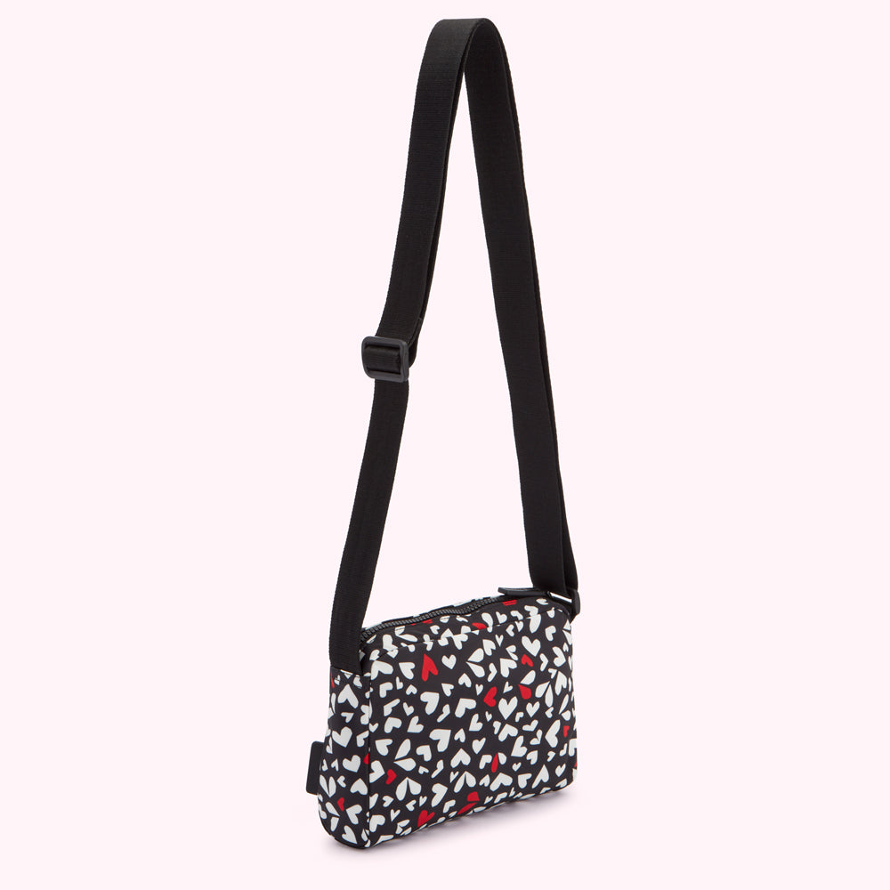 Black crossbody bag with a white and red heart pattern.
