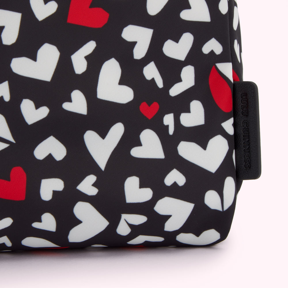 Close-up of a Lulu Guinness black cosmetic bag with a pattern of red and white hearts.