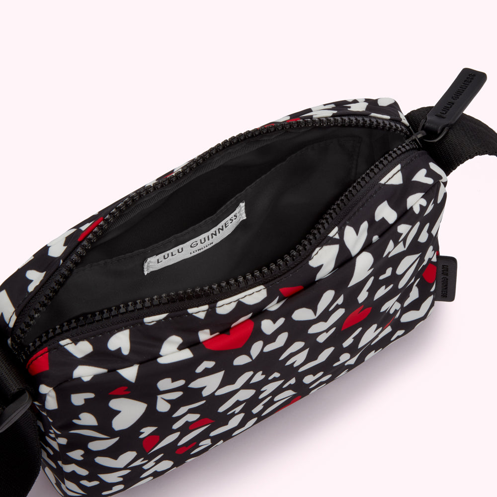 Black crossbody bag with a white and red heart pattern.