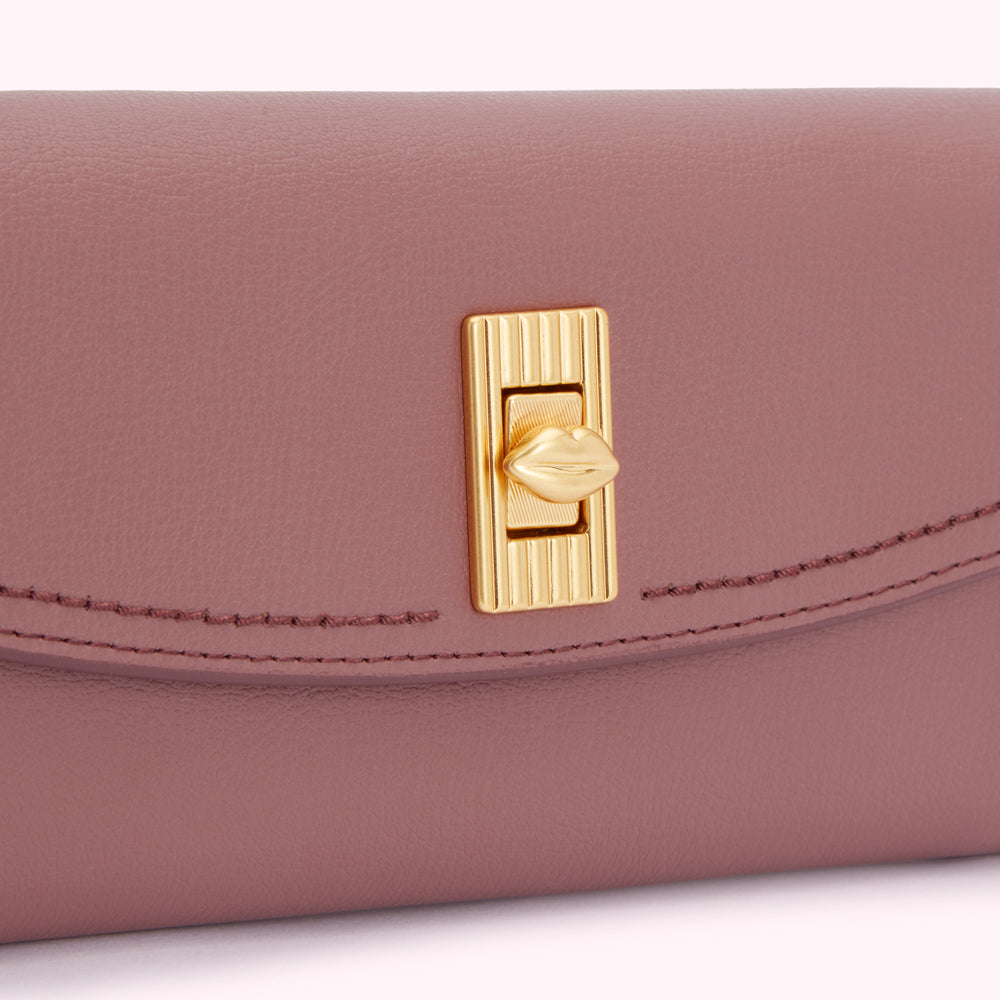 Close-up of a mauve leather wallet with a gold lip-shaped clasp.
