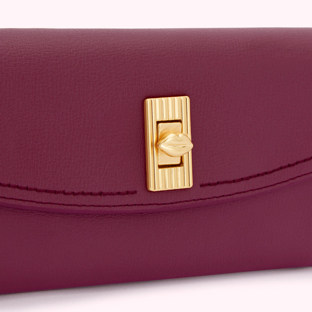 Close-up of a burgundy leather wallet with a gold lip-shaped clasp.