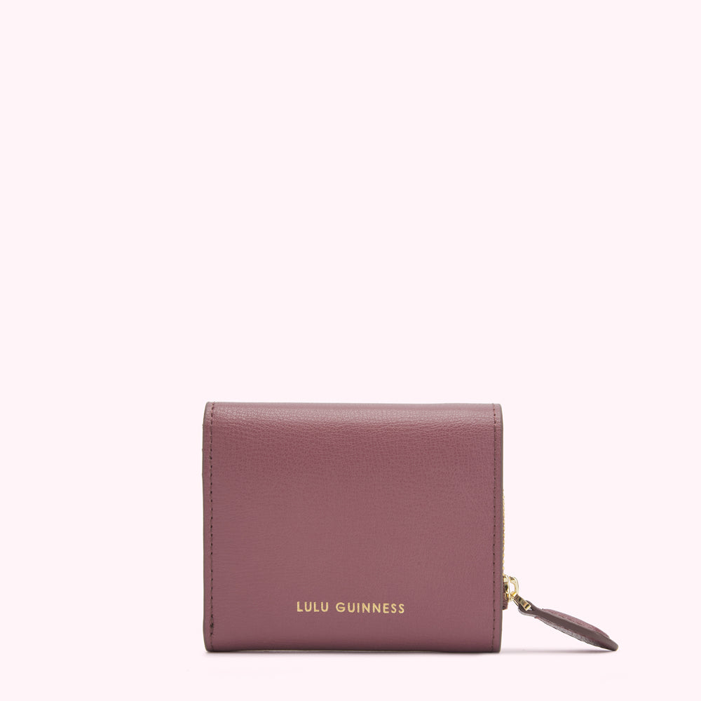 A dusty rose Lulu Guinness zip-around wallet against a white background.
