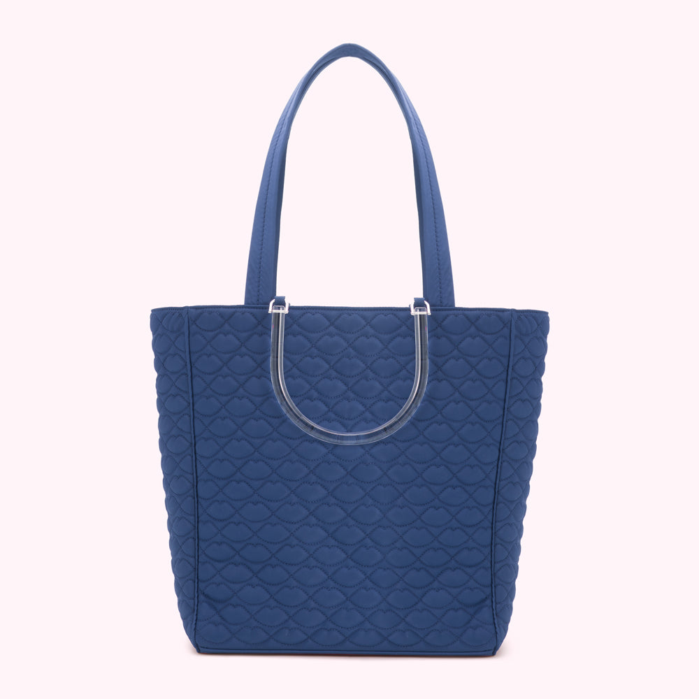 A navy blue quilted tote bag with clear handles.
