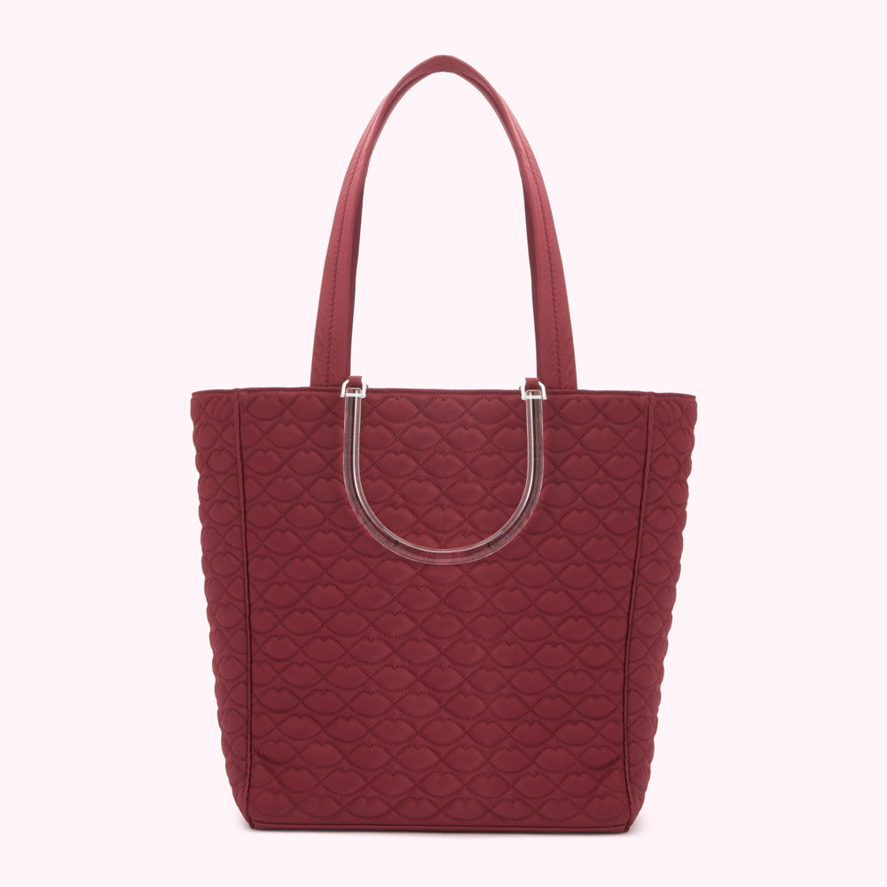 Burgundy quilted tote bag with clear handles and lip print pattern.
