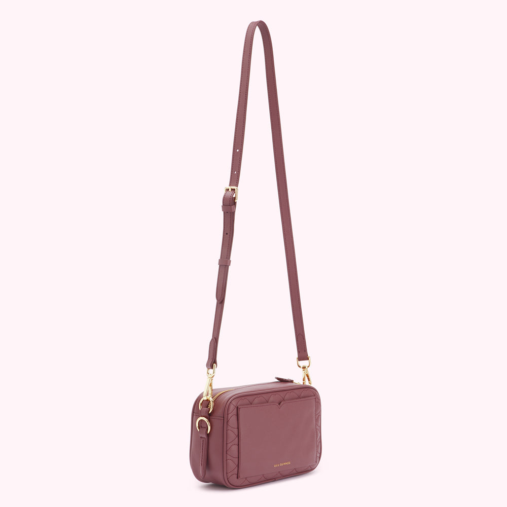 A dusty rose quilted crossbody bag with gold hardware.
