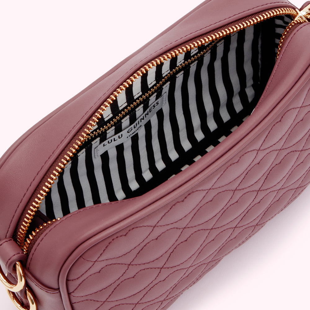 Interior of a mauve Lulu Guinness crossbody bag with a black and white striped lining.