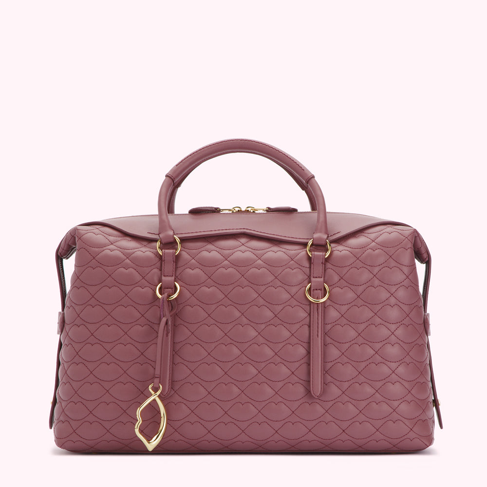 A mauve quilted leather handbag with gold-toned hardware and a lip-shaped charm.