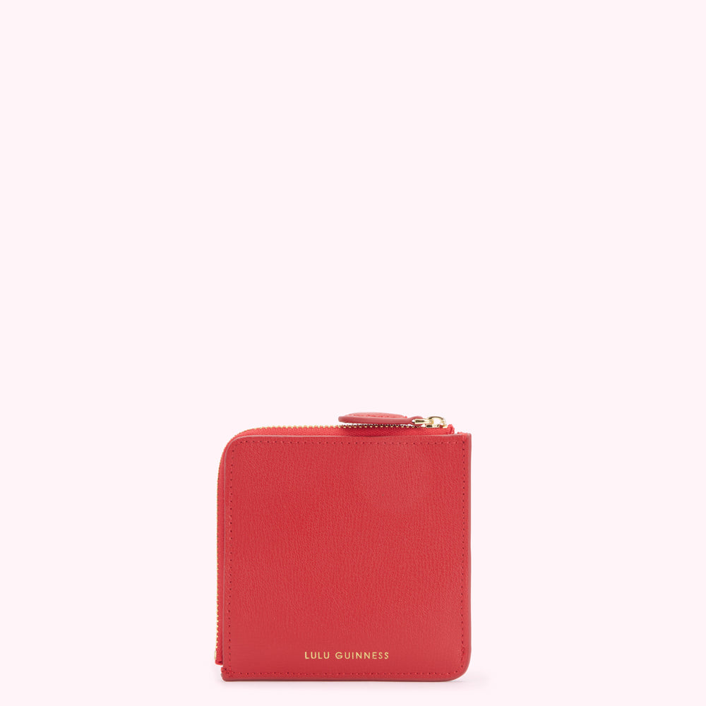Red Lulu Guinness zip-around purse on white background.
