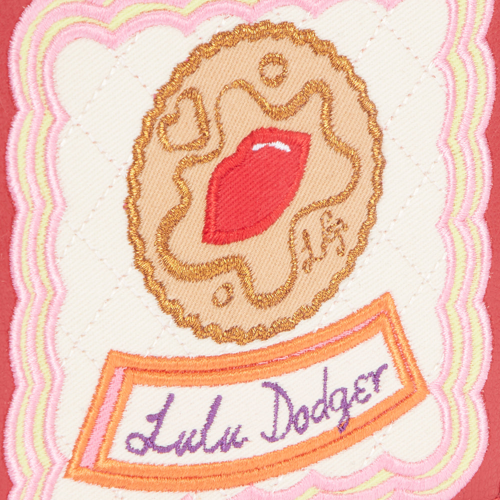 Embroidered patch on a red background featuring a biscuit with a red lip design and the text "Lulu Dodger".