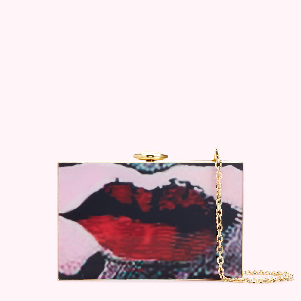 Rectangular clutch with a gold clasp and chain strap featuring an image of a pair of lips in shades of pink, red and black.
