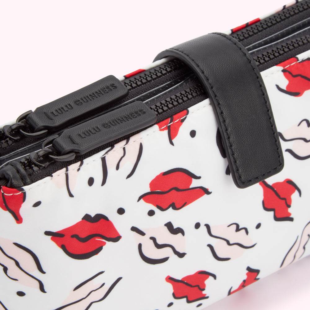 Close-up of a Lulu Guinness makeup bag with a white background featuring a red lips print and black zippers.