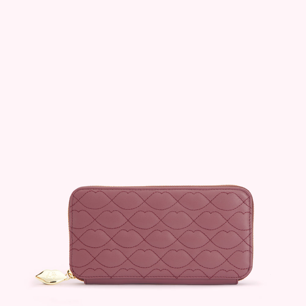 A mauve quilted zip-around wallet with a lip pattern.
