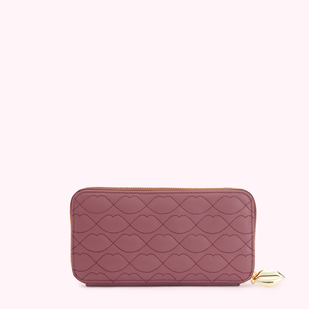 A mauve quilted zip-around wallet with a lip print and gold zipper and charm.