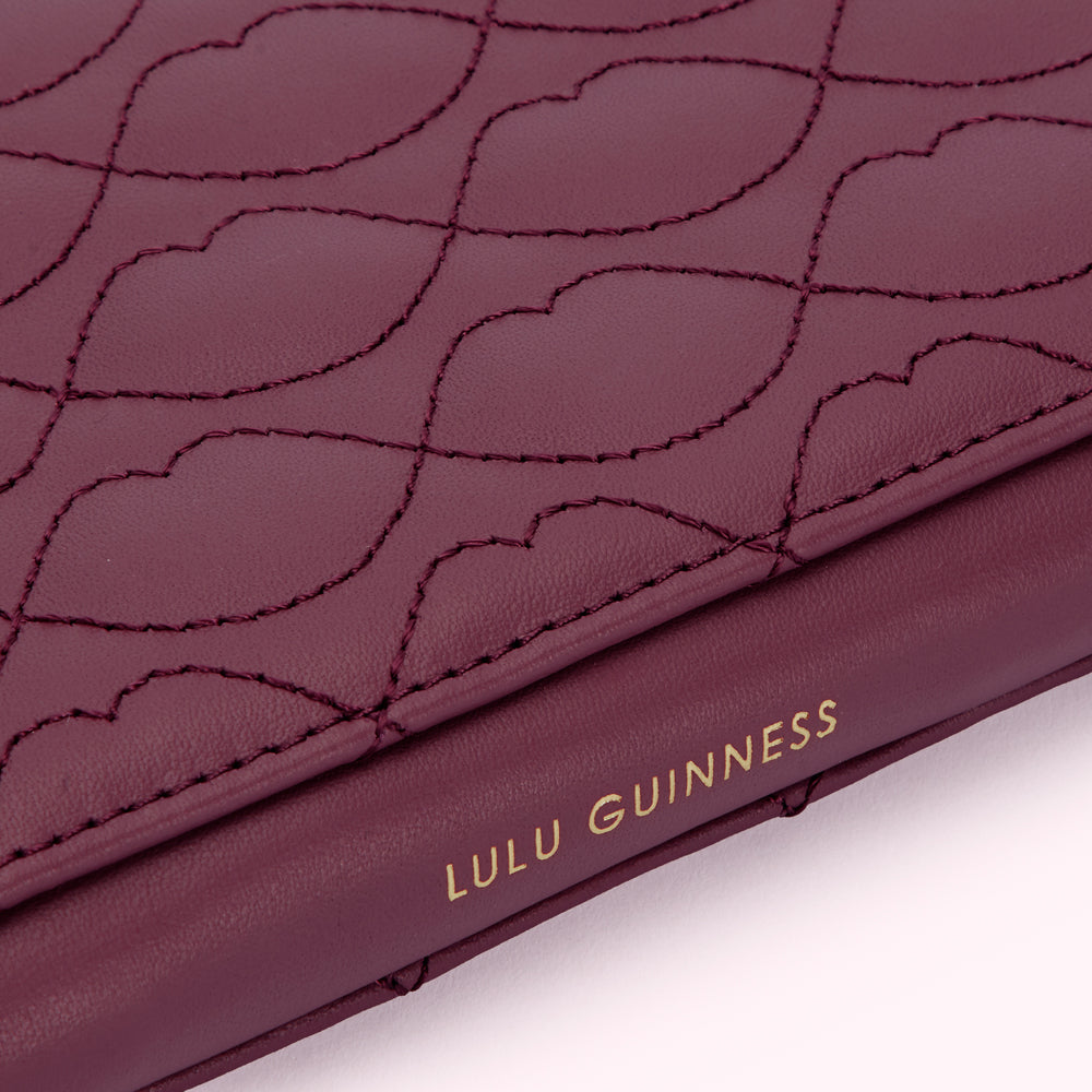 Close-up of a burgundy Lulu Guinness wallet with a quilted lip pattern and gold lettering.
