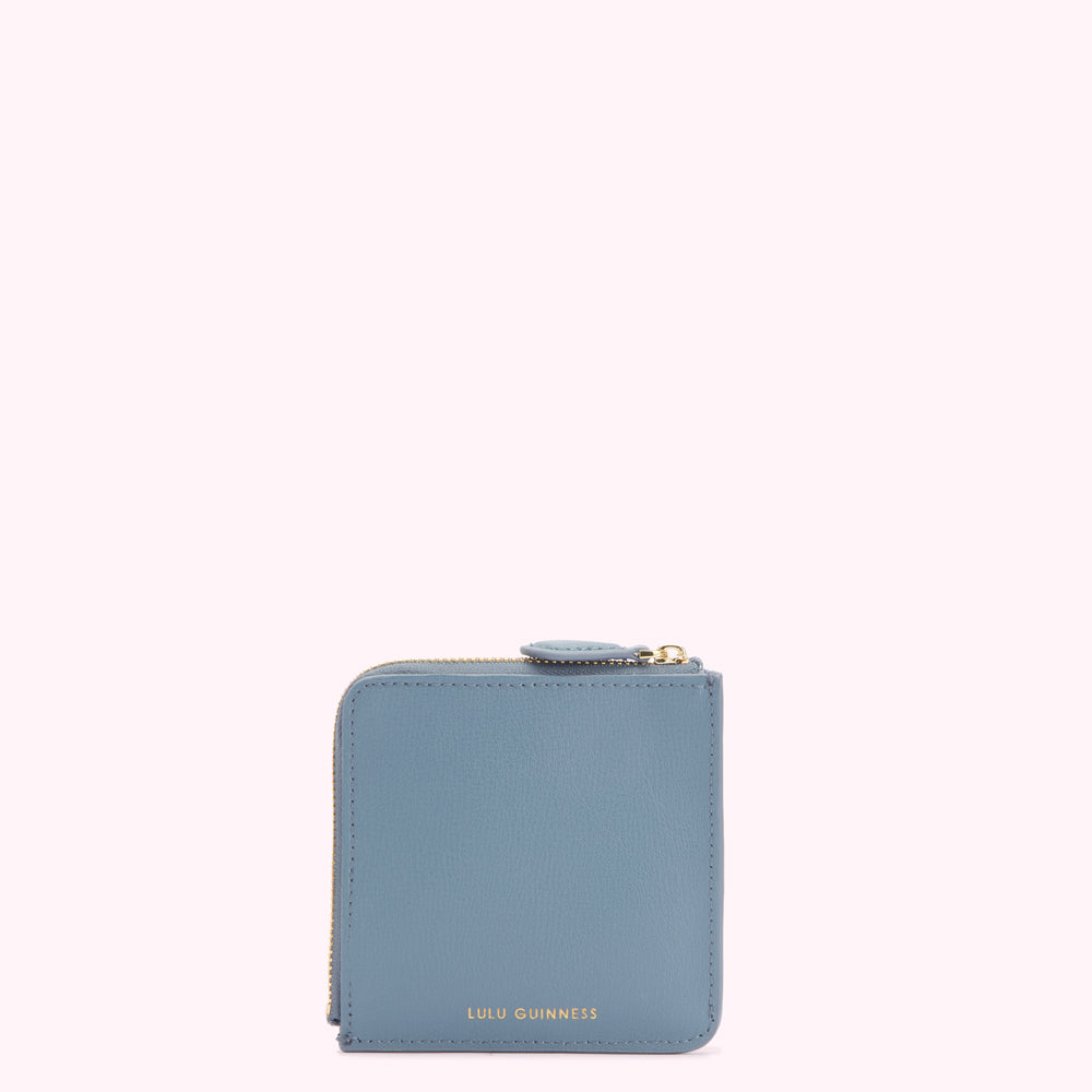 A dusty blue Lulu Guinness zip-around wallet against a white background.

