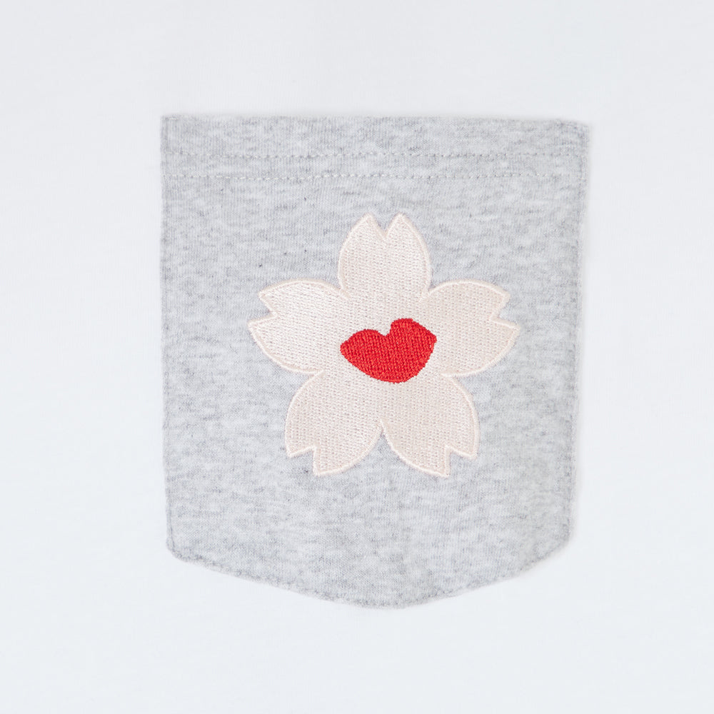 Grey pocket with embroidered off-white cherry blossom featuring a red lip in the centre.

