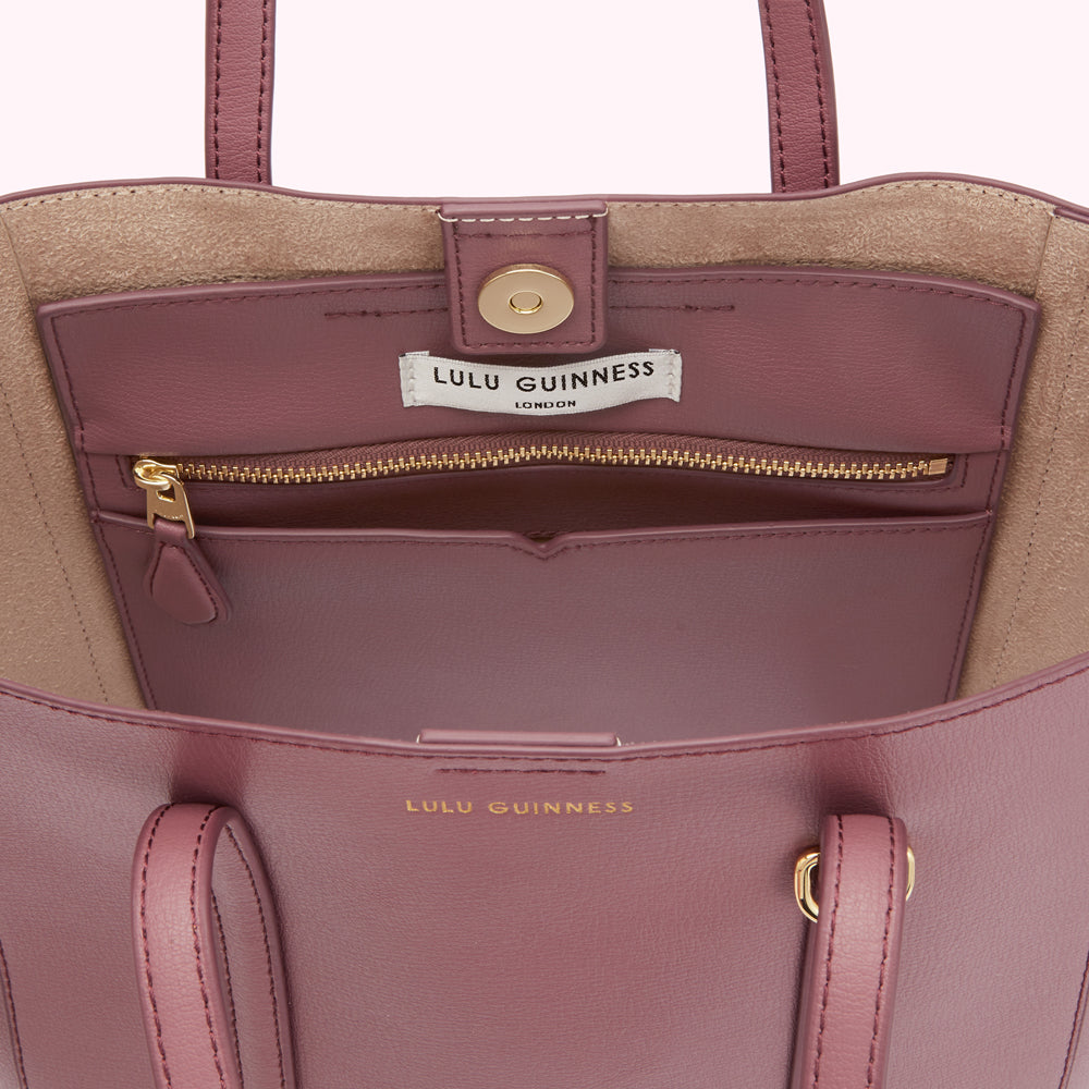 Interior of a dusty rose Lulu Guinness tote bag with a beige lining, gold zippered pocket, and gold-toned hardware.