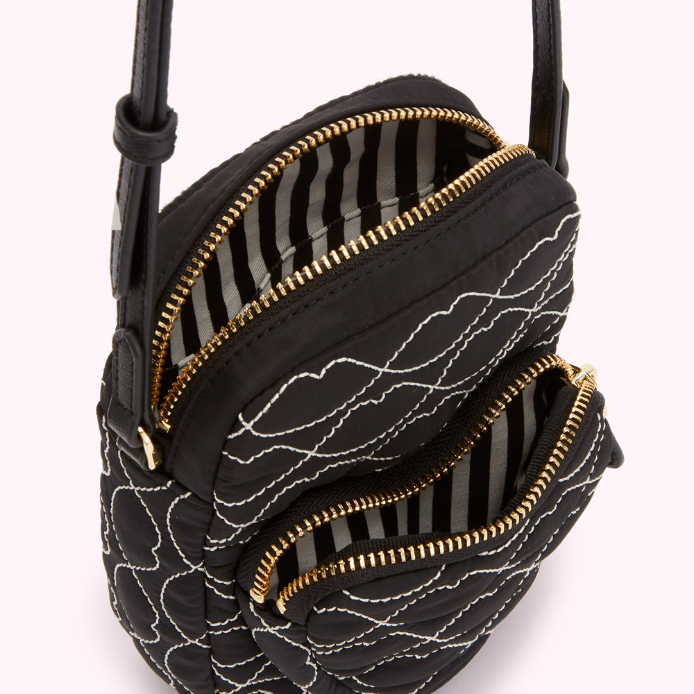 Black quilted crossbody bag with white stitching, featuring gold zippers and a black and white striped interior.

