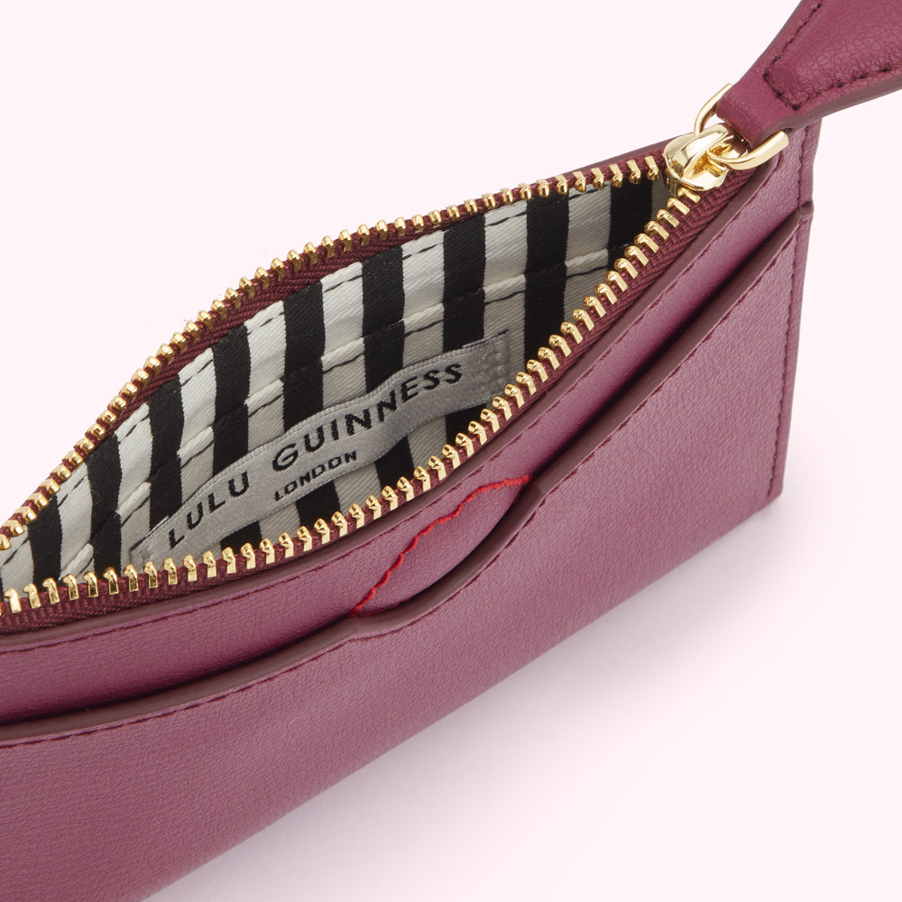 Close-up view of a burgundy Lulu Guinness zip-around purse with a black and white striped interior.