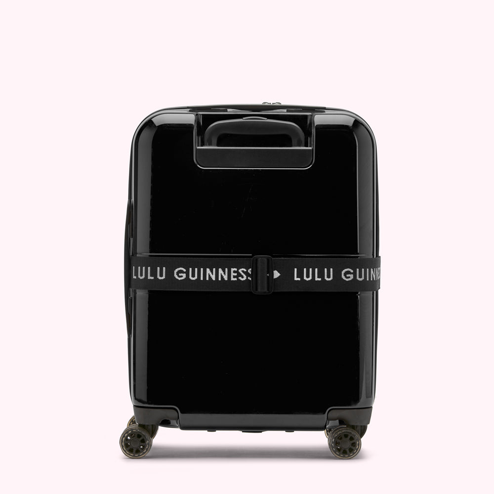 Black Lulu Guinness suitcase with a luggage strap.