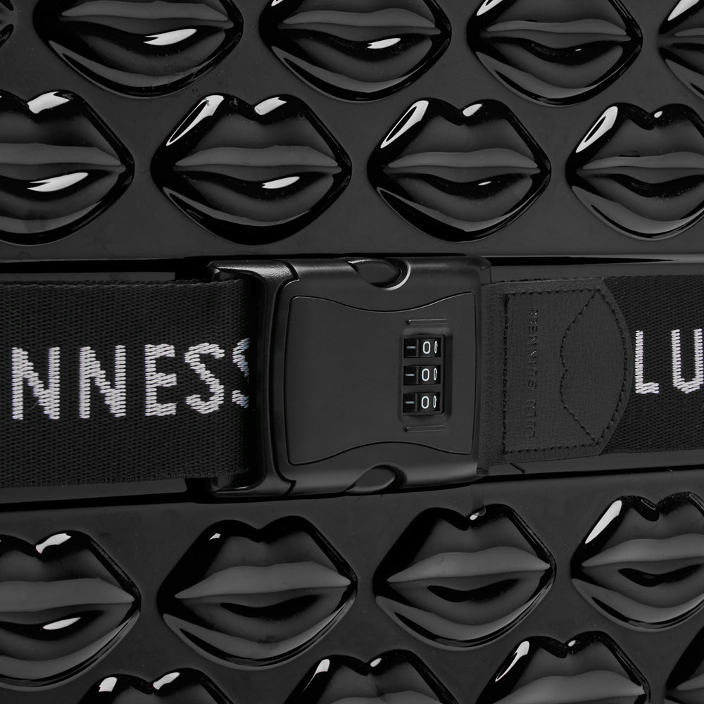 Close-up of a black suitcase with a lip print design and a combination lock.
