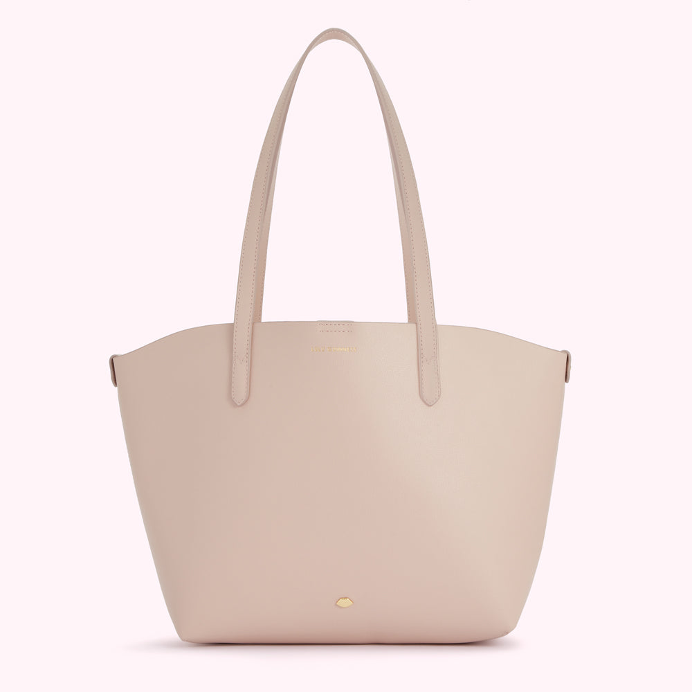 A pale pink leather tote bag with long handles and a small gold logo.
