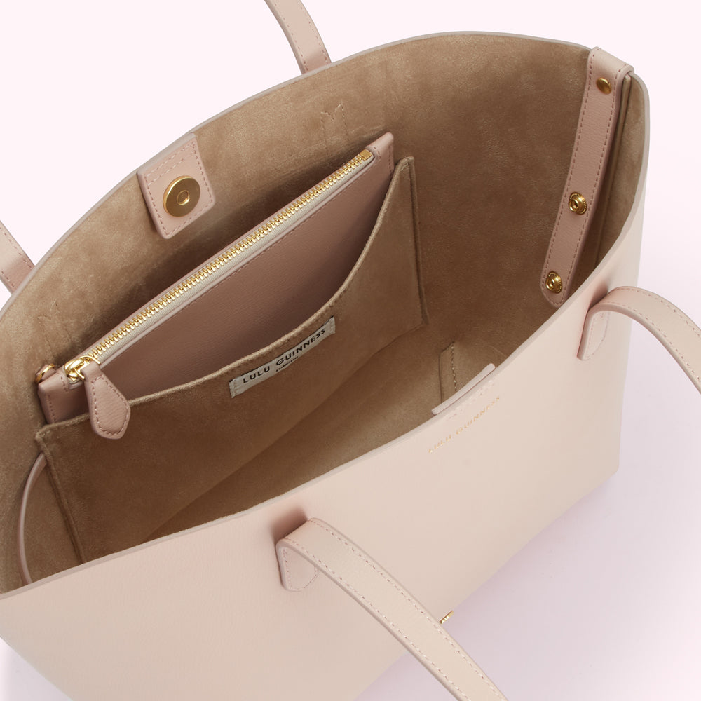 Inside of a blush pink Lulu Guinness tote bag showing the interior beige suede lining and a smaller zipped pocket.
