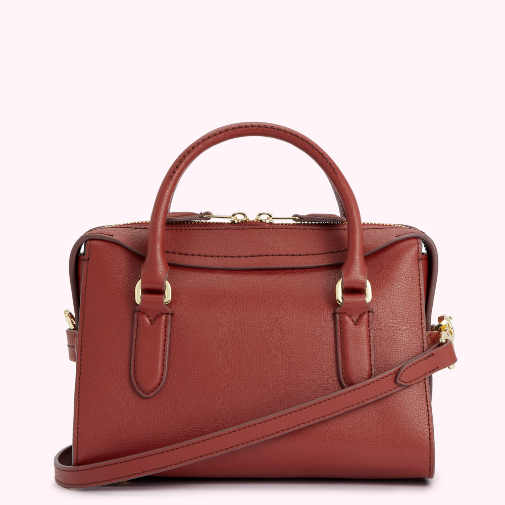 A rust-coloured leather handbag with gold hardware and a crossbody strap.
