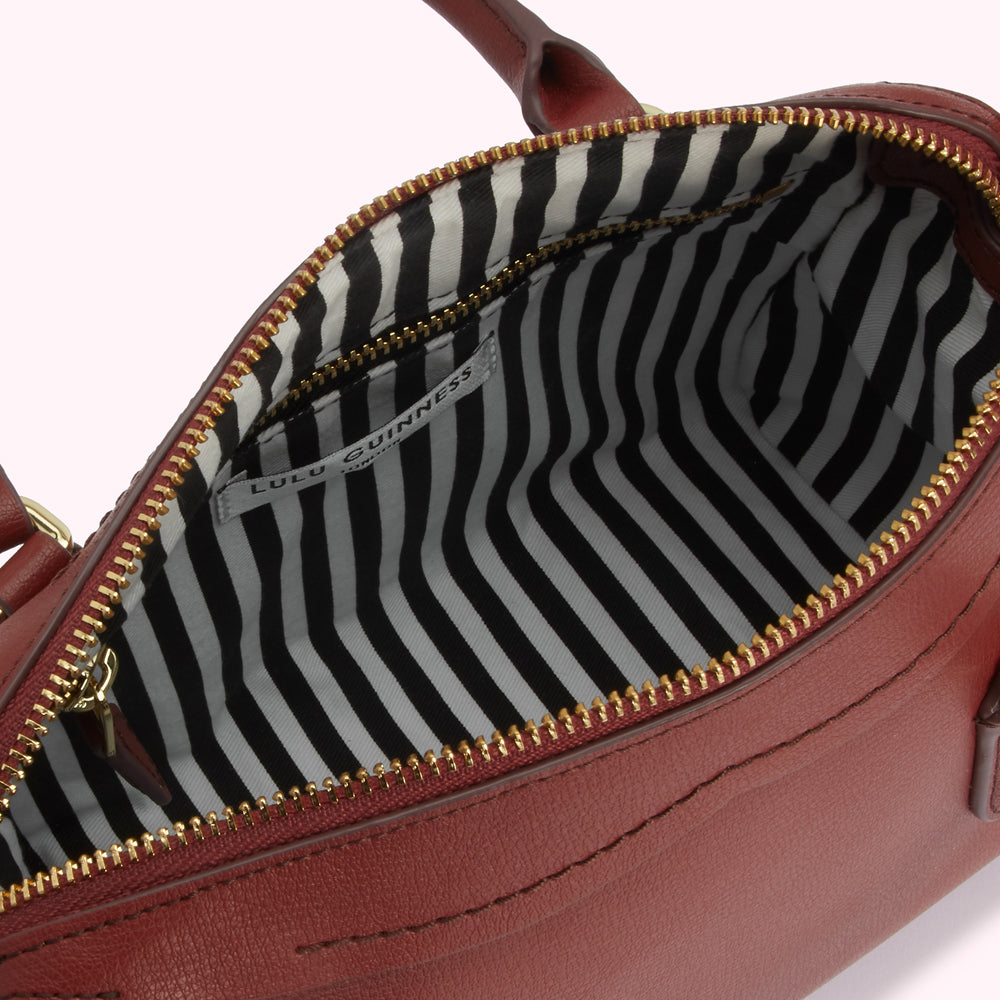 Interior of a burgundy Lulu Guinness handbag; the lining is black and white striped.
