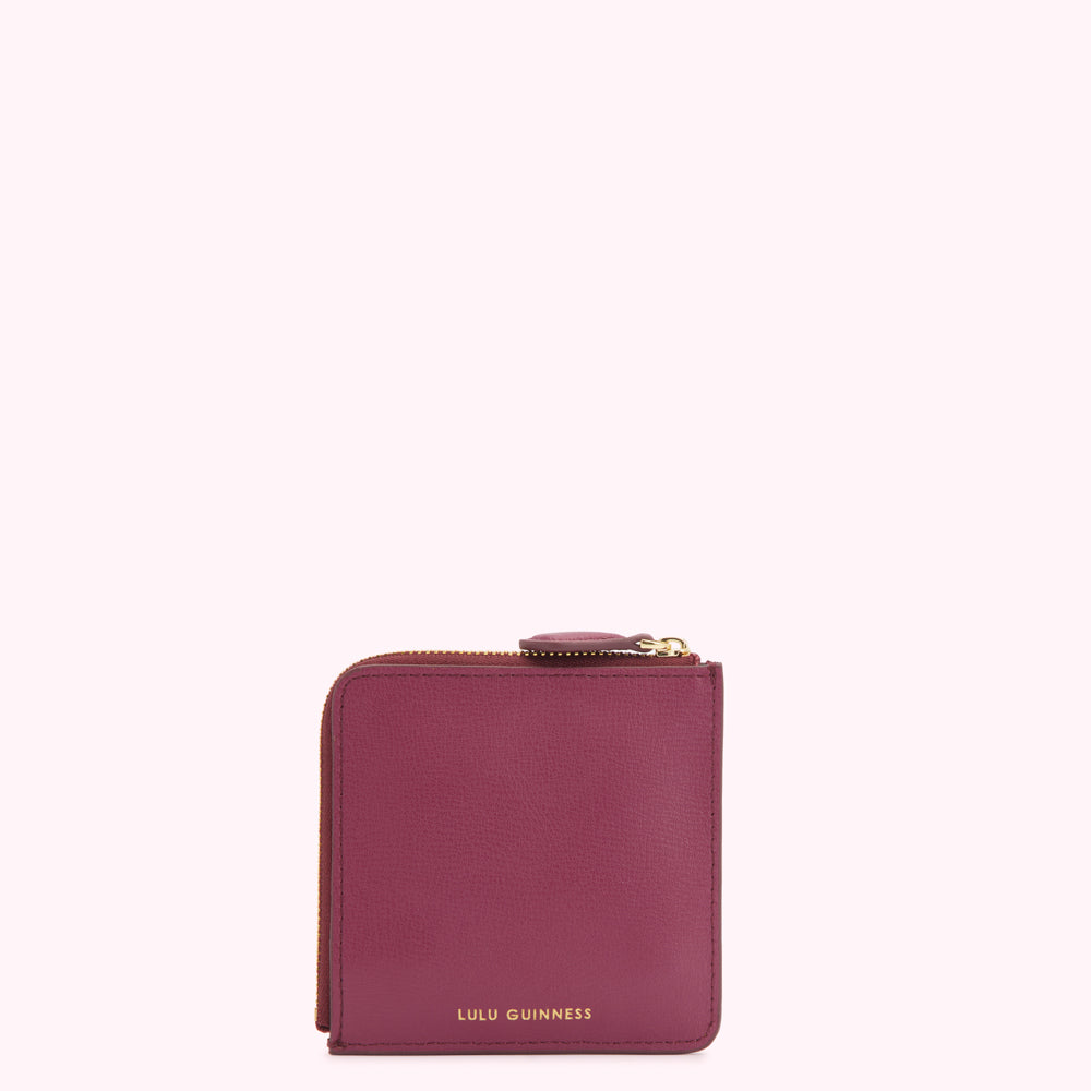A burgundy Lulu Guinness zip-around wallet against a white background.
