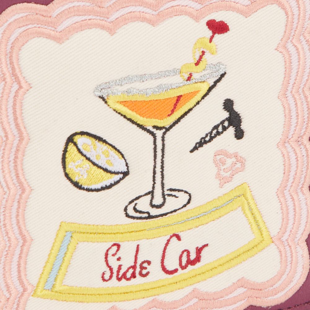 Embroidered patch on a burgundy background featuring a cocktail glass, lemon wedge, and the words "Side Car."