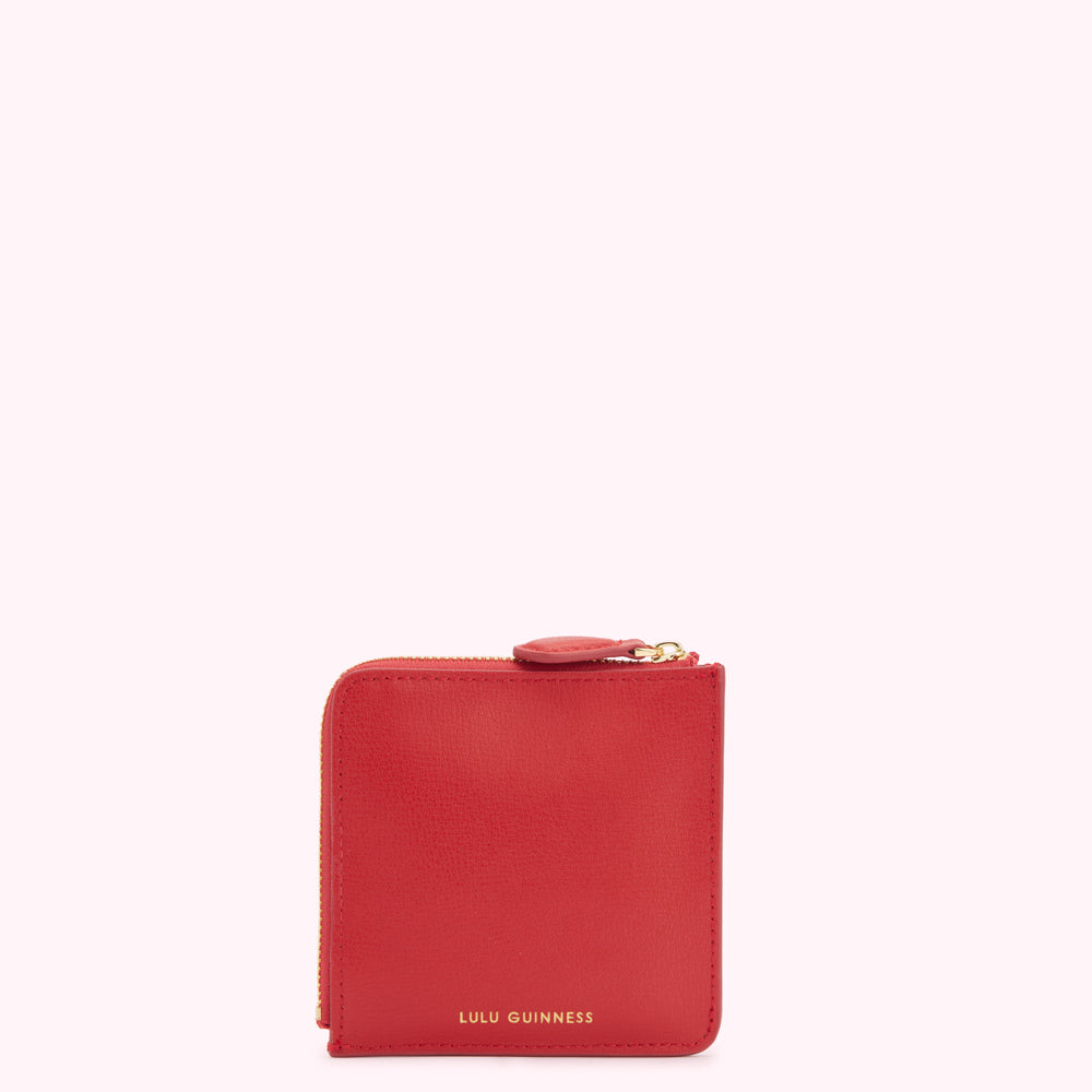 Red leather Lulu Guinness zip-around wallet against a white background.
