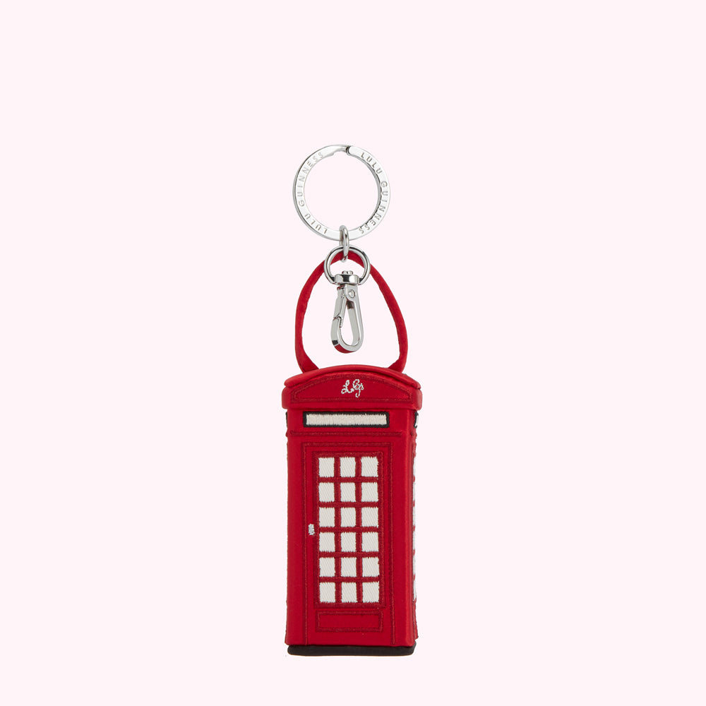 Red telephone booth-shaped keyring with silver ring and clasp, against a white background.
