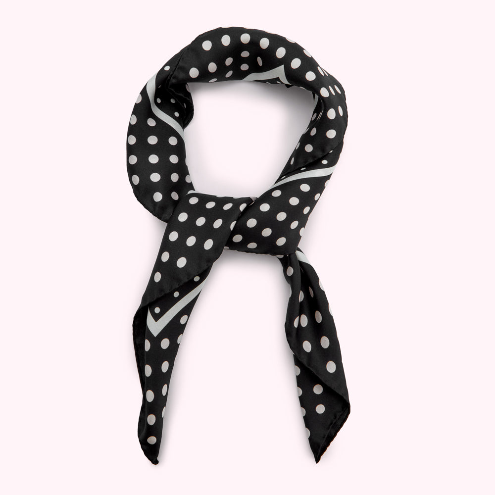 Black silk scarf with white polka dots, tied in a knot.
